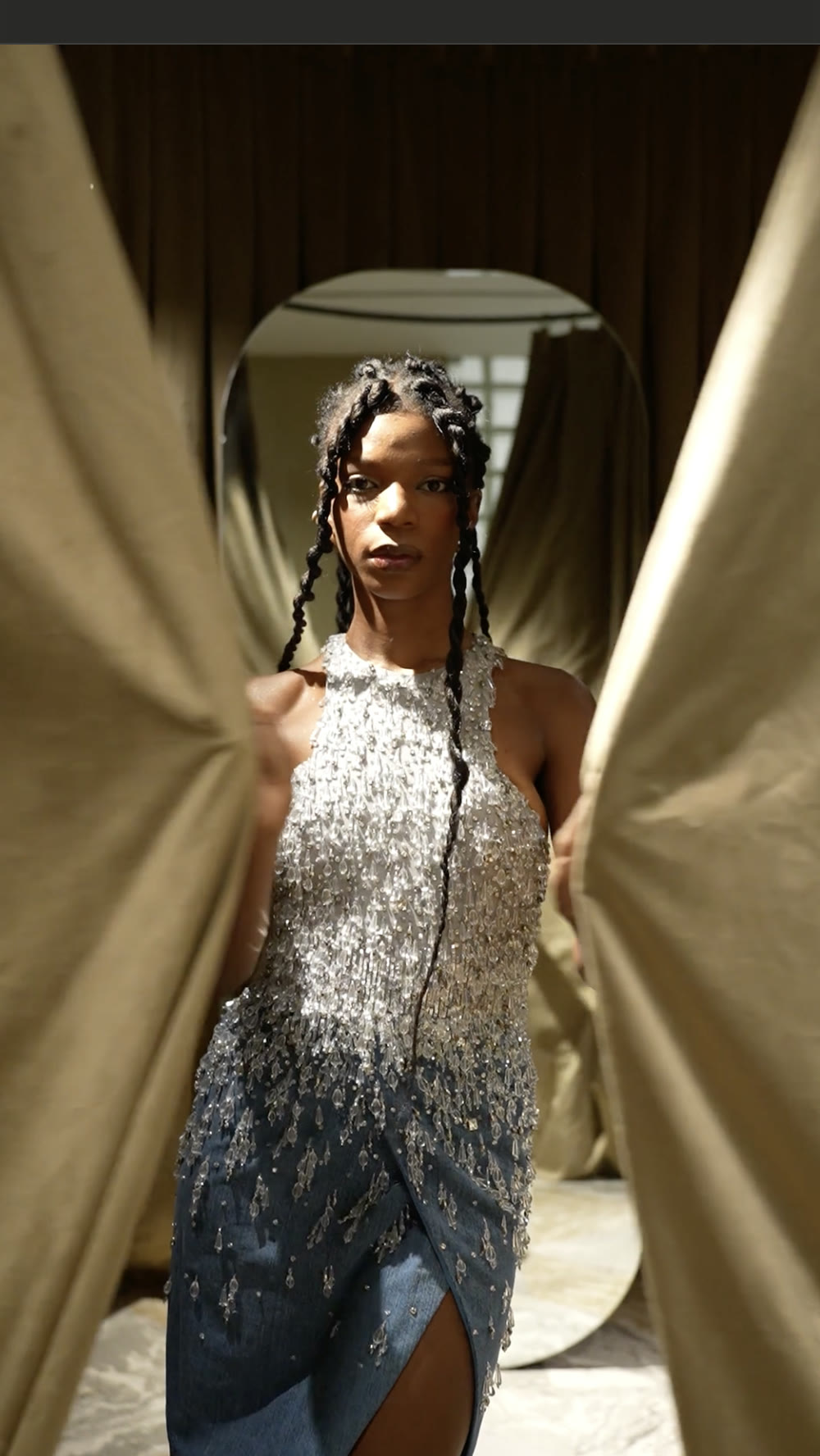 Fashion film still: model in a rhinestone dress with golden light