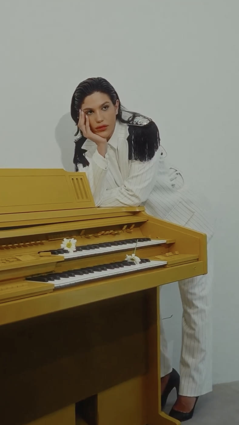 Modelo con traje blanco apoyada en un piano amarillo, campaña Santa Fe